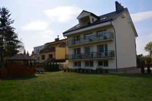 a large white building with balconies and a yard at Willa AGAT in Ciechocinek