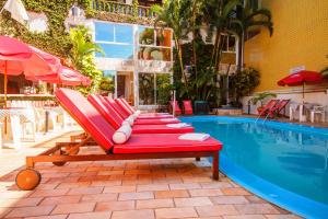 a row of red lounge chairs next to a swimming pool at Hotel Cabana Sui&ccedil;a in Guaratuba