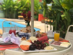 a table with a tray of cheese and fruit on it at Pousada Manjericão in Guaramiranga