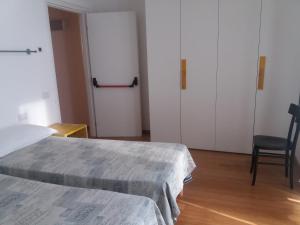 トリノにあるLuoghi Comuni Porta Palazzoのベッドルーム1室(ベッド2台、椅子1脚、ドア1台付)