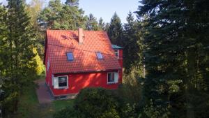 a red house with a red roof in the trees at Waldhufenhaus in Schöna in Reinhardtsdorf