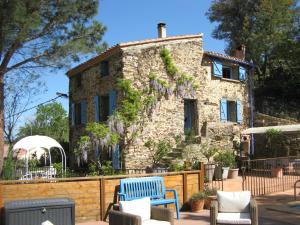 una vecchia casa in pietra con sedie e fiori blu di L'Oliveraie des 3 Mas a Saint-Michel-de-Llotes