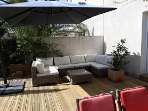 a patio with a couch and an umbrella at Maison de ville style échoppe in Le Bouscat