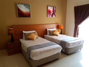 a bedroom with two beds and two lamps and a window at Cozy Escape @ Gold Coast Morib in Morib