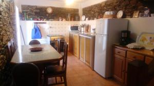 a kitchen with a table and a white refrigerator at Casa de Xisto in Arganil