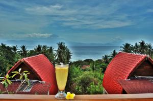 una copa de vino sentada en una mesa con dos cabañas en Petak Cottage en Nusa Penida