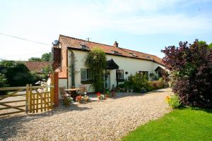 una casa con valla y entrada de grava en Olde Farm Holiday Cottages en Banham