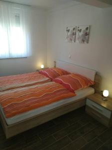 a bed with an orange comforter in a bedroom at Apartment Luzia in Banjole