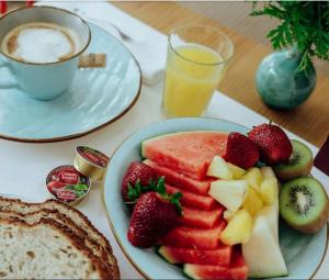 a table with a plate of fruit and a cup of coffee at Hotel Mar Azul & Surf in Suances