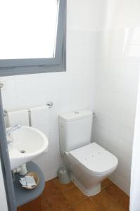 La salle de bains blanche est pourvue de toilettes et d'un lavabo. dans l'établissement Hostal Plaja i Pati de Can Plaja, à Palafrugell