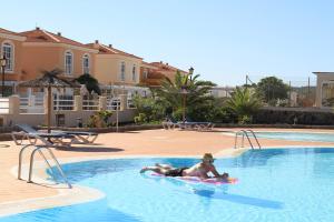 a man laying on a raft in a swimming pool at Villa Musica in Caleta De Fuste