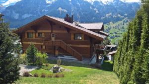 a large wooden house on a hill with mountains at Ferienwohnung Celina in Grindelwald