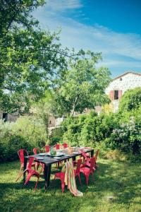 une table noire avec des chaises rouges dans la cour dans l'établissement Le Domaine du Fayet, à Sanilhac