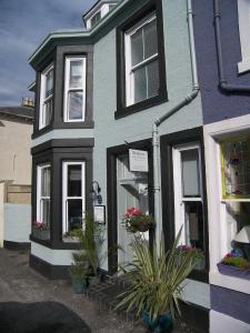 une maison bleue et blanche avec des plantes devant elle dans l'établissement ByTheSea Guest House, à Ayr