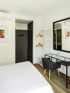 a bedroom with a bed and a desk and a mirror at Living-Sevilla Feria in Seville
