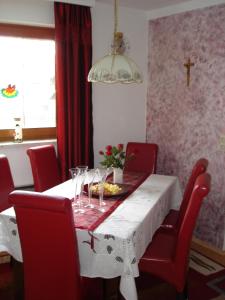 a dining room with a white table and red chairs at Ferienwohnung Hinterdorfer in Unterweissenbach