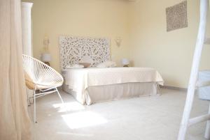 a white bedroom with a bed and a chair at Villa dei Ginepri in Gallipoli