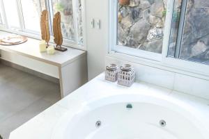 baño con bañera blanca y ventanas en Hotel Pousada do Bosque, en Ponta Porã