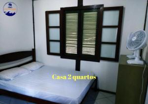 a bedroom with a bed and a window and a fan at Estacao Paraiso Chalé in Bertioga