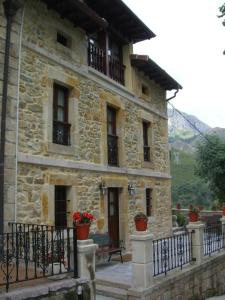 a stone building with a porch and a balcony at Apartamentos Rurales La Husteriza in Ruenes