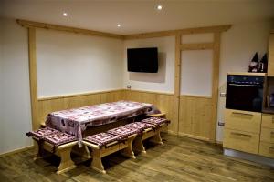 ein Zimmer mit einem Tisch mit Bänken und einem Fernseher in der Unterkunft Enrosadira in Molveno