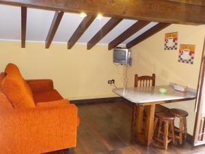 uma sala de estar com um sofá e uma mesa em Apartamentos Rurales La Husteriza em Ruenes