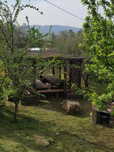 a wooden pergola with a bench in a yard at La Mariola Apartments in Santa Luce