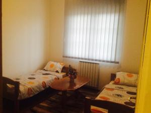 Habitación con 2 camas, mesa y ventana en Apartman br.1, en Bijeljina