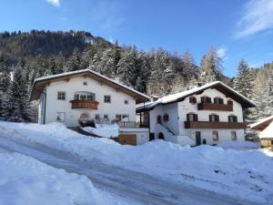a house in the snow next to a road at Apartment Cësa Zinch in Ortisei