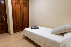 サンタクルス・デ・テネリフェにあるPiso en el Corazón de la Ciudadのベッドルーム1室(ベッド1台付)、木製キャビネットが備わります。