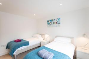 2 camas en una habitación con paredes blancas en Camana, en St Ives