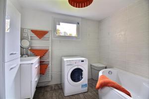 a laundry room with a washing machine and a tub at Maison à la campagne in Louargat