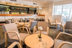 a restaurant with tables and chairs and a bar at Bay Plaza Hotel in Wellington
