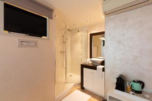 La salle de bains est pourvue d'une douche et d'une télévision murale. dans l'établissement Aby, à Cannes