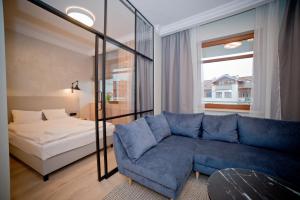 a living room with a blue couch and a bed at Lucy Apartment Neptun Park - Hav Aparts in Gdańsk