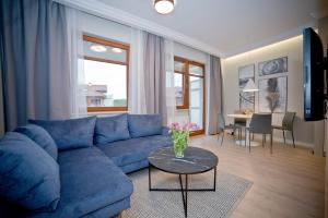ein Wohnzimmer mit einem blauen Sofa und einem Tisch in der Unterkunft Lucy Apartment Neptun Park - Hav Aparts in Danzig