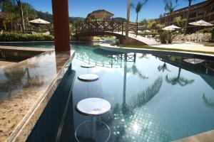 uma piscina com dois bancos e uma ponte em Flat particular no Resort em Angra Dos Reis em Angra dos Reis