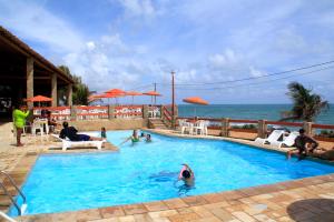 a group of people in a swimming pool near the ocean at Chalemar Hotel Pousada in Baía Formosa