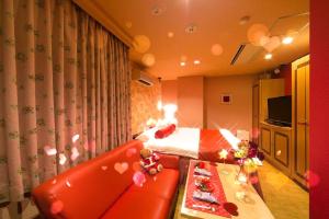 名取市Grand Hotel Staymore -Adult Only的酒店客房配有红色的沙发和床。