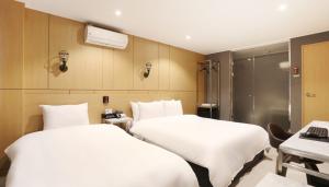 a hotel room with two beds and a shower at Louis Hotel in Gangneung