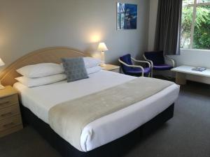 una camera d'albergo con un grande letto e sedie di Pacific Motor Inn a Mount Maunganui Altre 35 foto