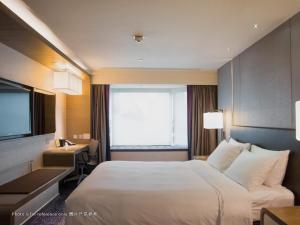 a hotel room with a bed and a desk and a television at Royal Plaza Hotel in Hong Kong +30 photos