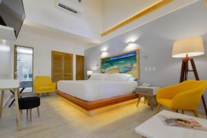 a bedroom with a large white bed and yellow chairs at Casa Las Palmas Hotel Boutique in San Andrés