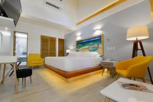 a bedroom with a white bed and yellow chairs at Casa Las Palmas Hotel Boutique in San Andrés