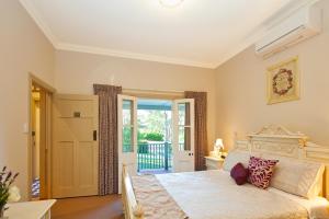 a bedroom with a large bed and a balcony at Brantwood Cottage Luxury Accommodation in Blackheath