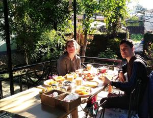 un uomo e una donna seduti a un tavolo con del cibo di Yeti Guest House a Pokhara