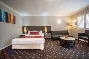 a hotel room with a large bed and a couch at Ramada Hotel & Suites by Wyndham Cabramatta in Cabramatta