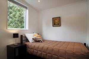 um quarto com uma cama e uma janela em Nut Point Cottage em West Melton