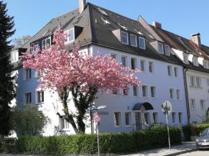 ein weißes Gebäude mit einem blühenden Baum davor in der Unterkunft Boardinghouse München-Laim in München