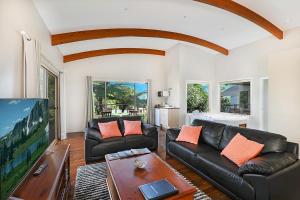 uma sala de estar com sofás de couro preto e uma mesa em Maleny Terrace Cottages em Maleny